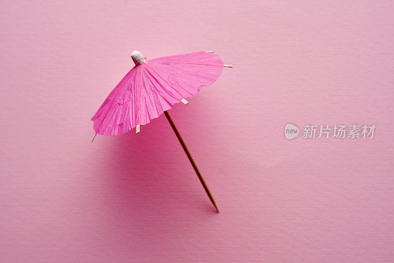 粉红色鸡尾酒伞孤立在粉红色的背景上。