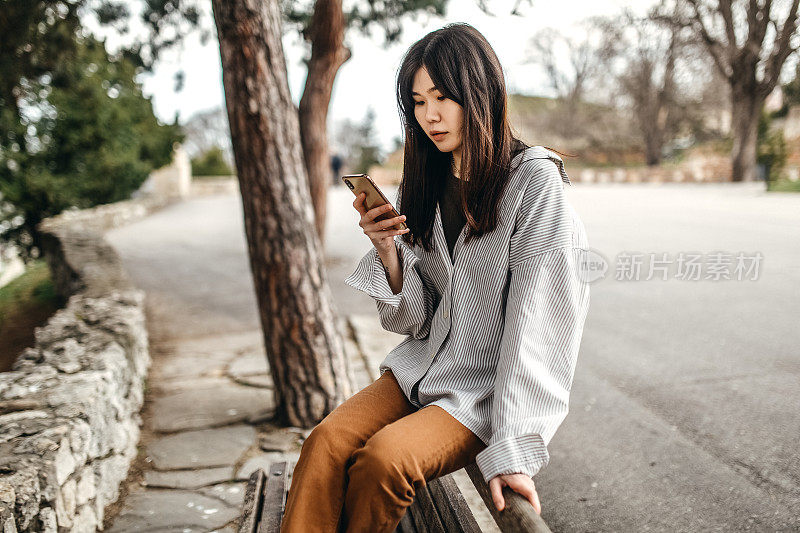 中国年轻女子在公园里玩智能手机