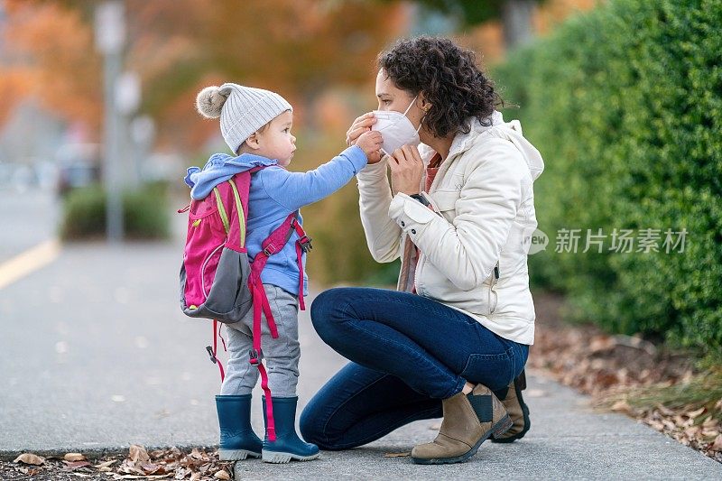 妈妈在学校和蹒跚学步的女儿说再见