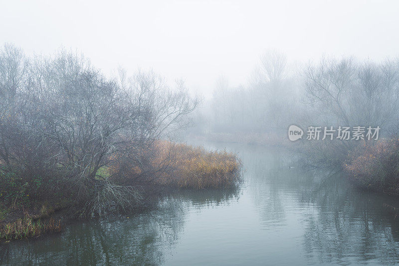 雾蒙蒙的灰色湖泊和多云的天空景观