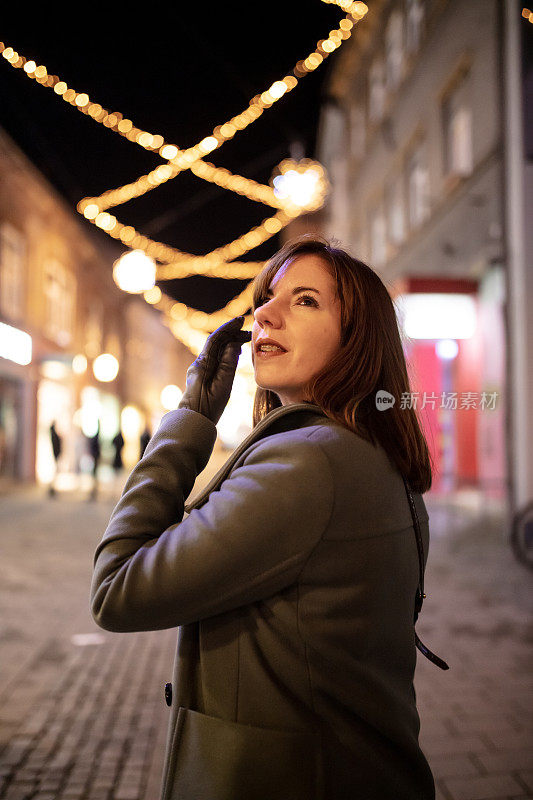 有思想的女人在夜晚站在灯火通明的城市仰望