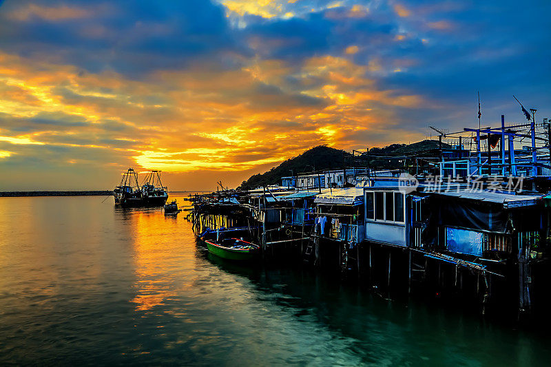 在渔村和附近的海边，盖在水中的铁皮房子里，夕阳发出红光。