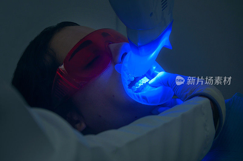 用紫外线照射牙科病人并戴防护眼镜口腔卫生员