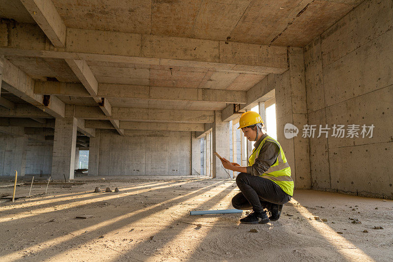 一位亚洲女建筑工人正在工地上使用平板电脑