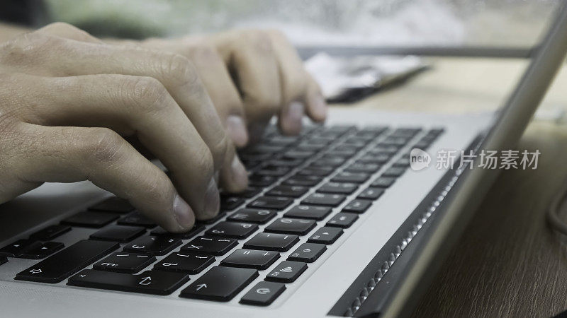 男人在笔记本电脑键盘上打字的特写。资料片。自由职业者或商人使用笔记本电脑工作。男人的手在笔记本电脑上打印文本或文章