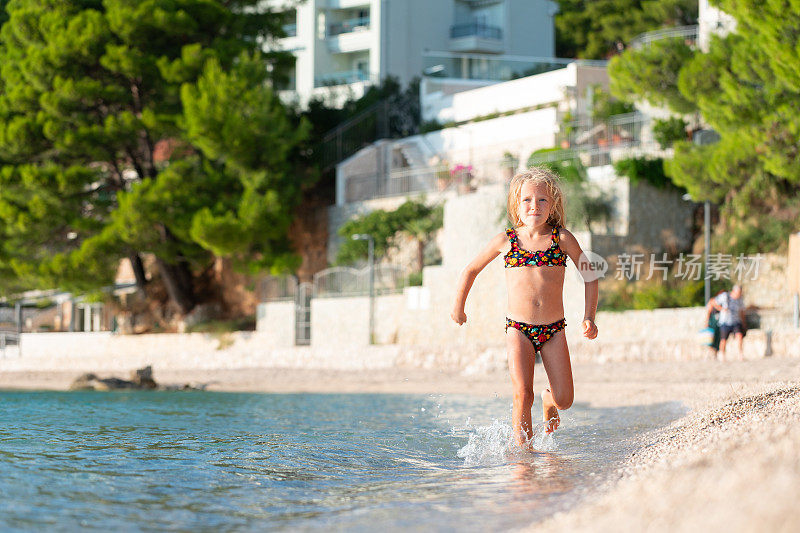 小女孩在海滩旁的海水中奔跑。