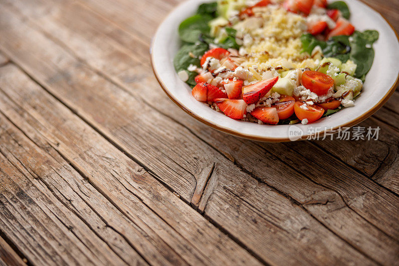 多彩的健康沙拉盘放在一张旧木桌的右上角