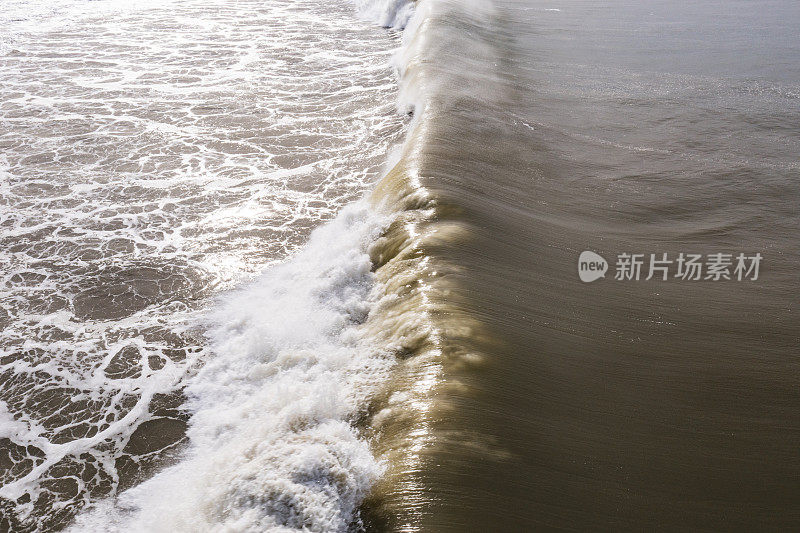 正上方的波浪在肮脏的棕色污染海水中破碎