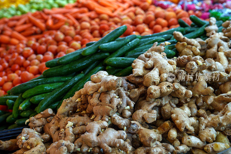农贸市场的摊位上摆放着生姜、黄瓜、西红柿、胡萝卜等各种有机蔬菜