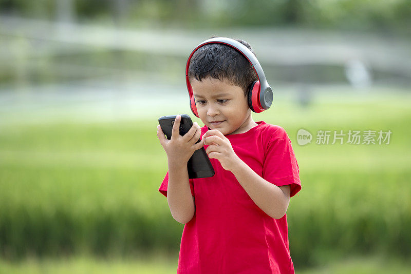 蹒跚学步的男孩用耳机听音乐