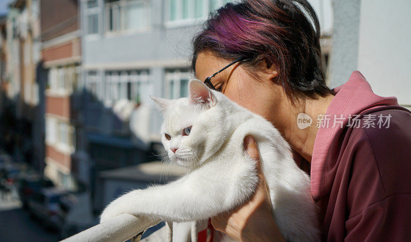 一名妇女在她家的窗户边满怀爱意地拥抱着她的猫。