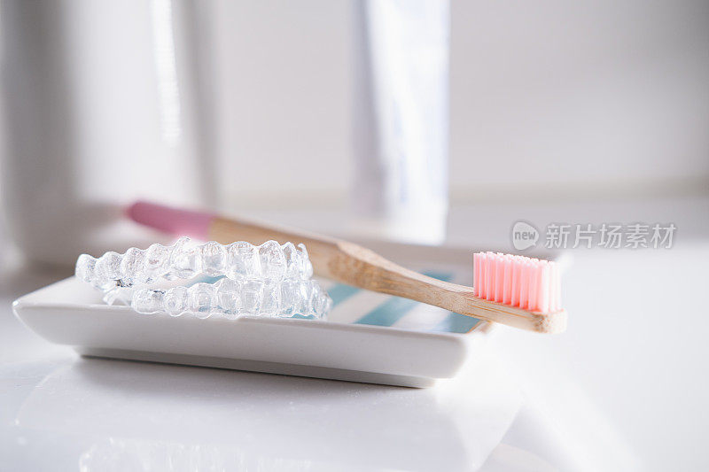 透明牙齿矫正器和粉红色木制牙刷。