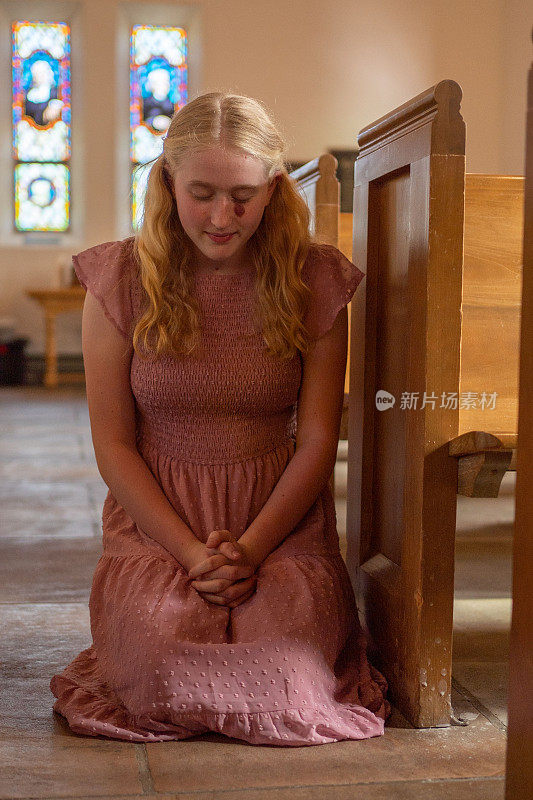 一名年轻女子跪在教堂里祈祷，双手合十祈祷