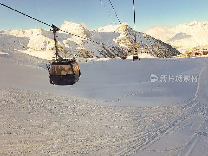 贡多拉缆车穿过白雪覆盖的斜坡，带着滑雪者在法国弧区度假时往返于山顶