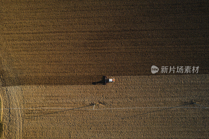 农民驾驶履带式拖拉机犁地和动力耙地，使土壤表面结皮破裂，以方便植物在干燥的土壤上生长和播种