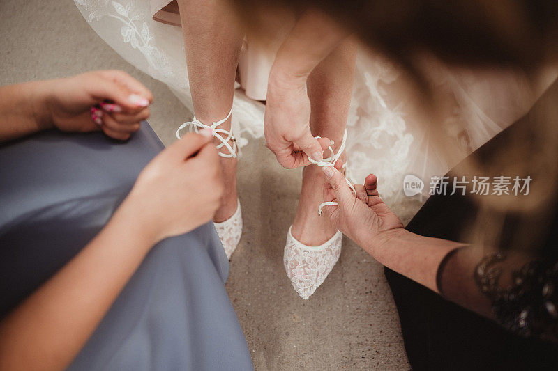 新娘在伴娘的帮助下穿鞋