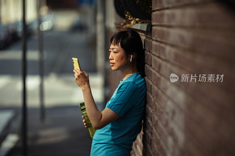 一名年轻的日本女子在健身后使用智能手机休息