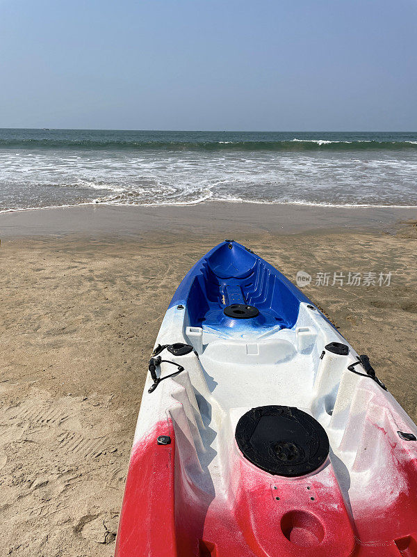 海滩的红色，白色和蓝色的海上皮艇出租的特写图像在Palolem海滩，果阿，假日假期，清澈的蓝色阳光明媚的天空和大海与破碎的海浪，高架的观点，重点在前景