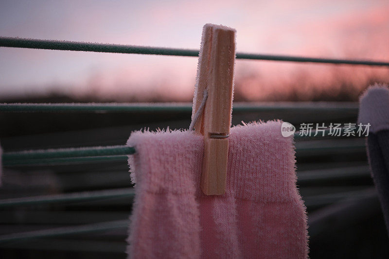 冬天早晨日出时晾衣绳上一只冻住的粉色袜子的特写。