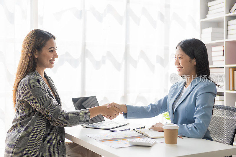 两位自信的女商人在成功会议、联系、问候和合作团队工作过程中握手。分析营销计划