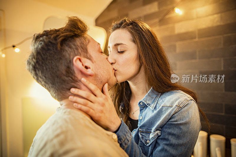 一对年轻夫妇在厨房里拥抱亲吻