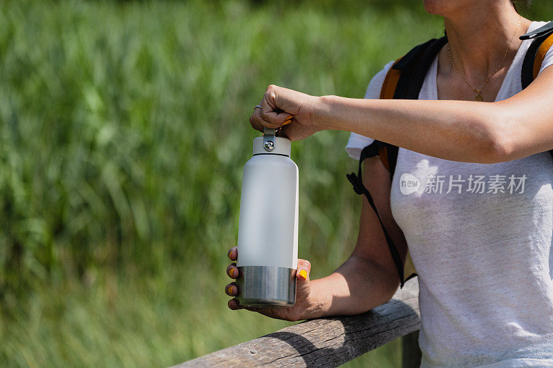 一个女人在水上打开保温瓶。