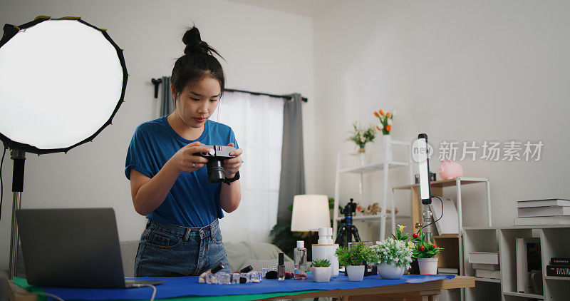 年轻的女摄影师在家庭摄影棚里整理产品