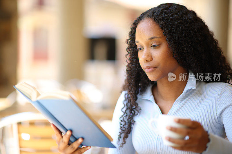 黑人妇女一边看纸质书一边喝咖啡