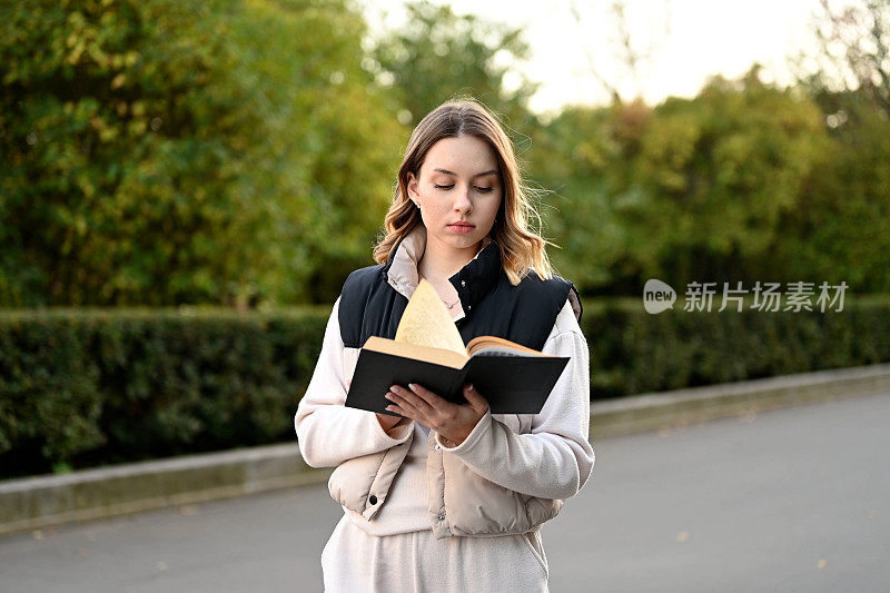 一个女人在公园里散步，看一本纸质书