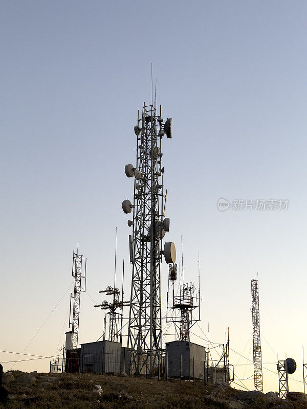 在落日的天空中，一座金属通讯塔巍然耸立。