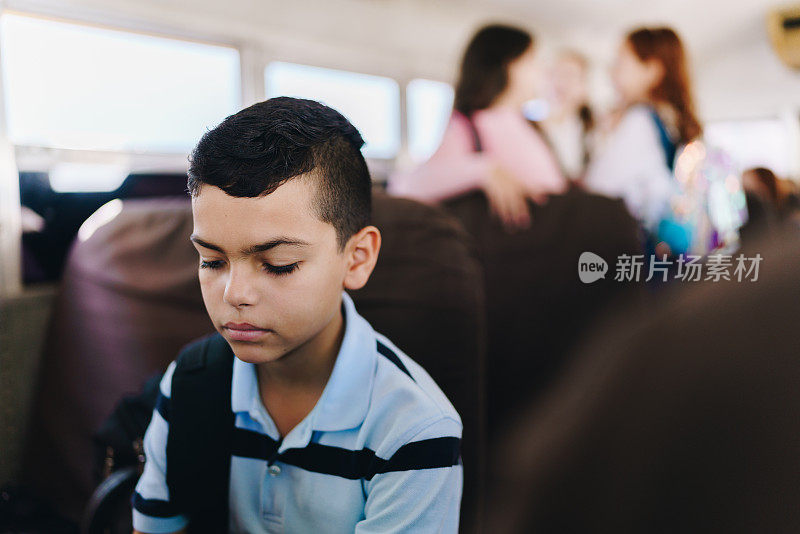 悲伤的小男孩坐着校车去上学