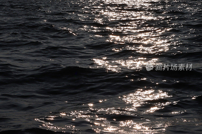 海水表面水平的全帧图像，阳光在波涛汹涌的水面上闪闪发光，波浪背景