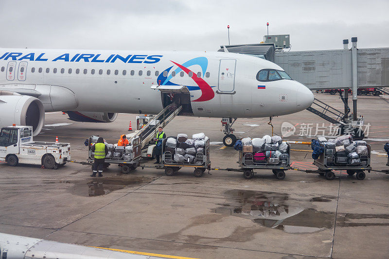 2024年4月6日，俄罗斯圣彼得堡:普尔科沃机场将行李装上飞机。真是糟糕的一天。有几辆装有手提箱的手推车。