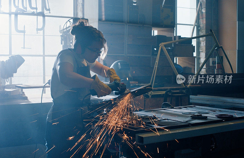 金属，工作和妇女与钢磨床和铁切割刀片的火花在车间生产。在电焊厂从事工具、制造和维修工作，使用人工和电机