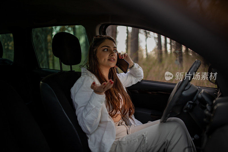 年轻的压力大的女人坐在森林附近的车里打电话