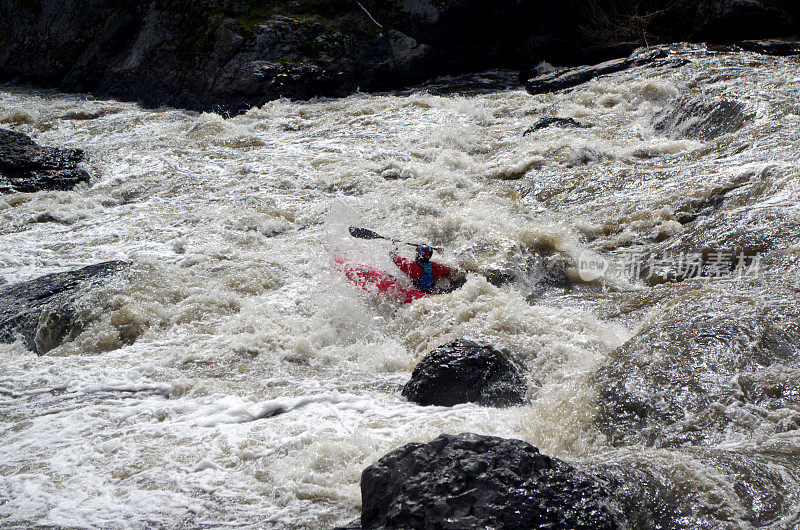 一个皮划艇手在波涛汹涌的河流中穿梭于岩石之间
