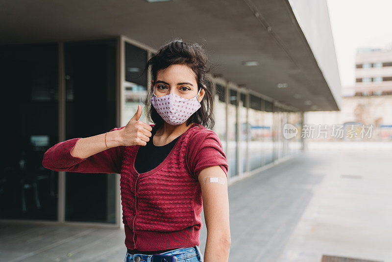 千禧年混血妇女展示她刚接种疫苗的手臂