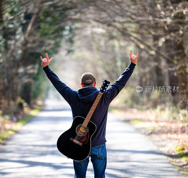 在宽阔的马路上，背着吉他的男人用喇叭做手势