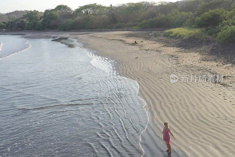 鸟瞰图的女人走下沙滩在日出