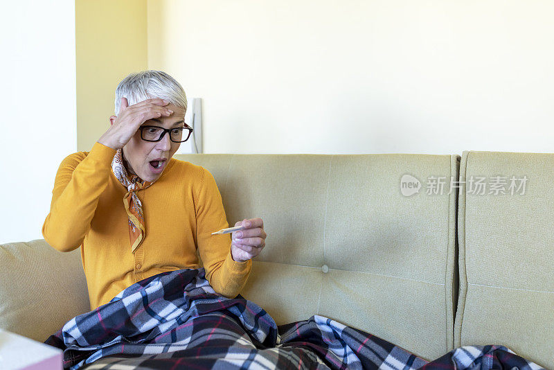 一个生病的老女人在床上高烧的照片。