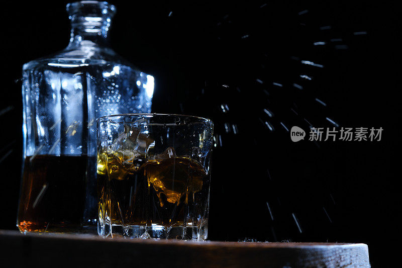 冰块掉进棕色木头上的威士忌酒杯里