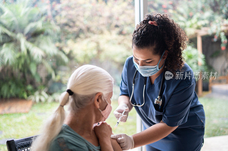 护士佩戴防护口罩为老年妇女接种疫苗