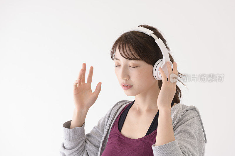 一名年轻女子戴着耳机，看着白色背景前的一侧。
