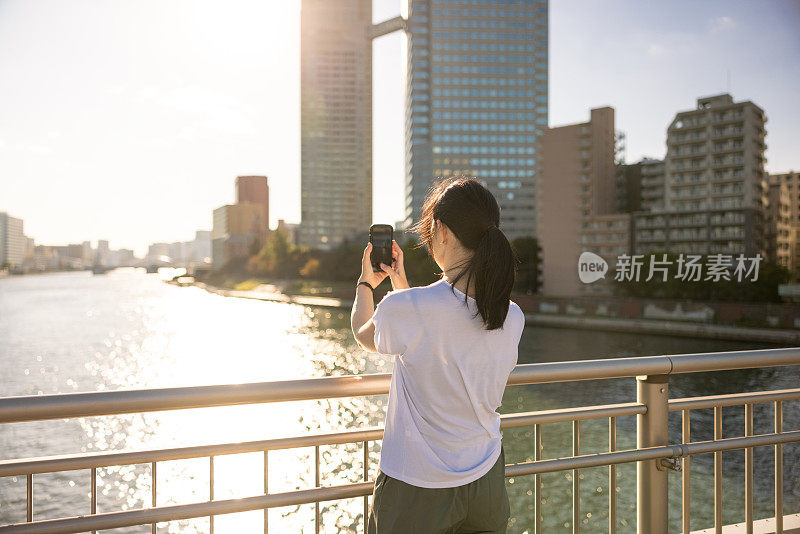 日落时分，女人在桥上拍照