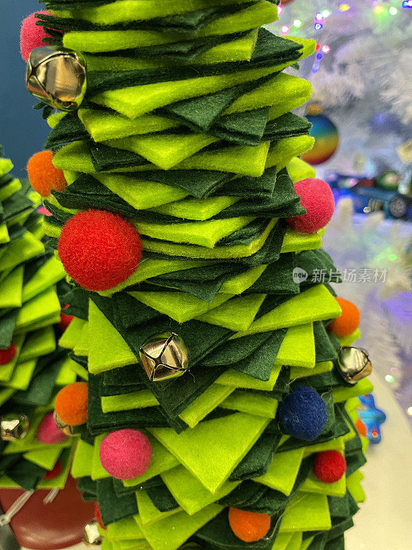 近距离拍摄的模型圣诞树，由浅绿色和深绿色的毛毡方块围绕着木杆旋转而成，聚焦前景