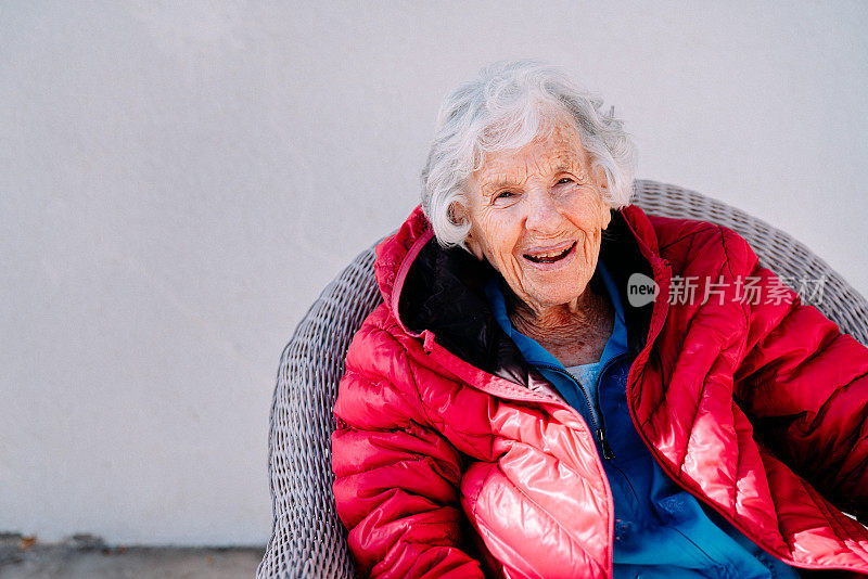 快乐的100岁老年白人妇女坐在户外与复制空间的冬天