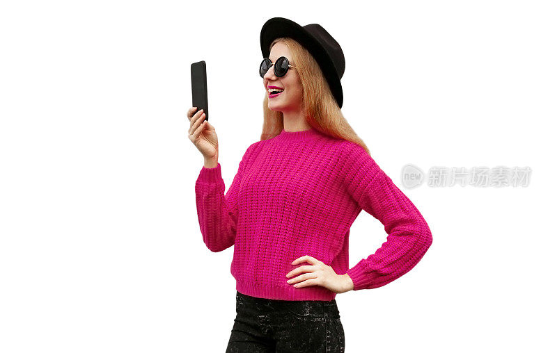时尚年轻女子的肖像与智能手机穿着粉红色针织毛衣和黑色圆帽孤立在白色背景
