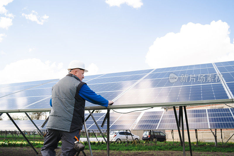 一个工程师站在一个大的太阳能电池板旁的低角中景拍摄