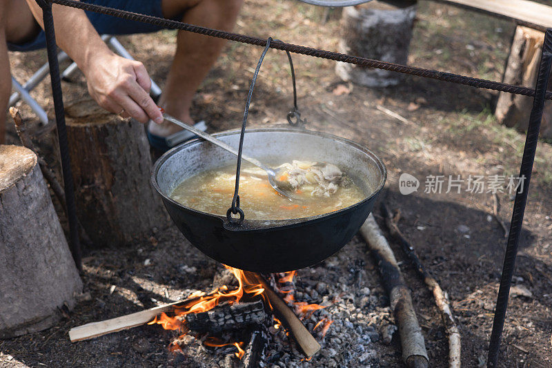 人类在野外用大锅煮饭。在森林的背景下，锅和篝火。露营生活。当地的旅游