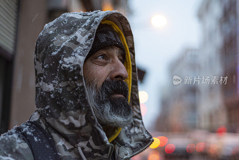 冬天，满脸胡须的中年男子在下雪的日子里在伊斯坦布尔街头的肖像。